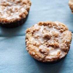 Butter crumb muffins with glaze on blue background.