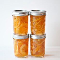 Citrus marmalade in glass jars with metal lids on a white background.