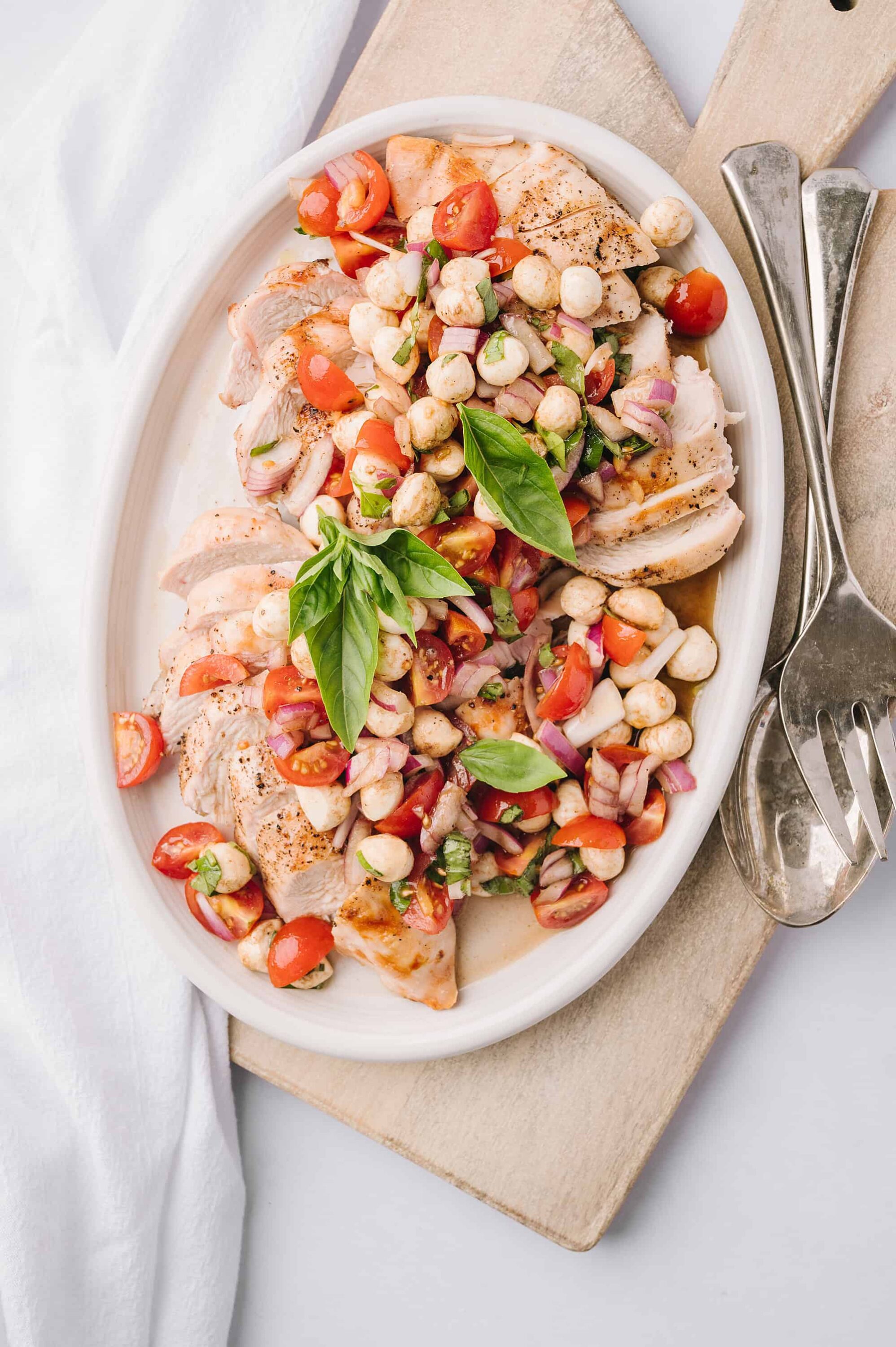 Juicy roasted chicken with chickpea, cherry tomato salad garnished with basil leaves.