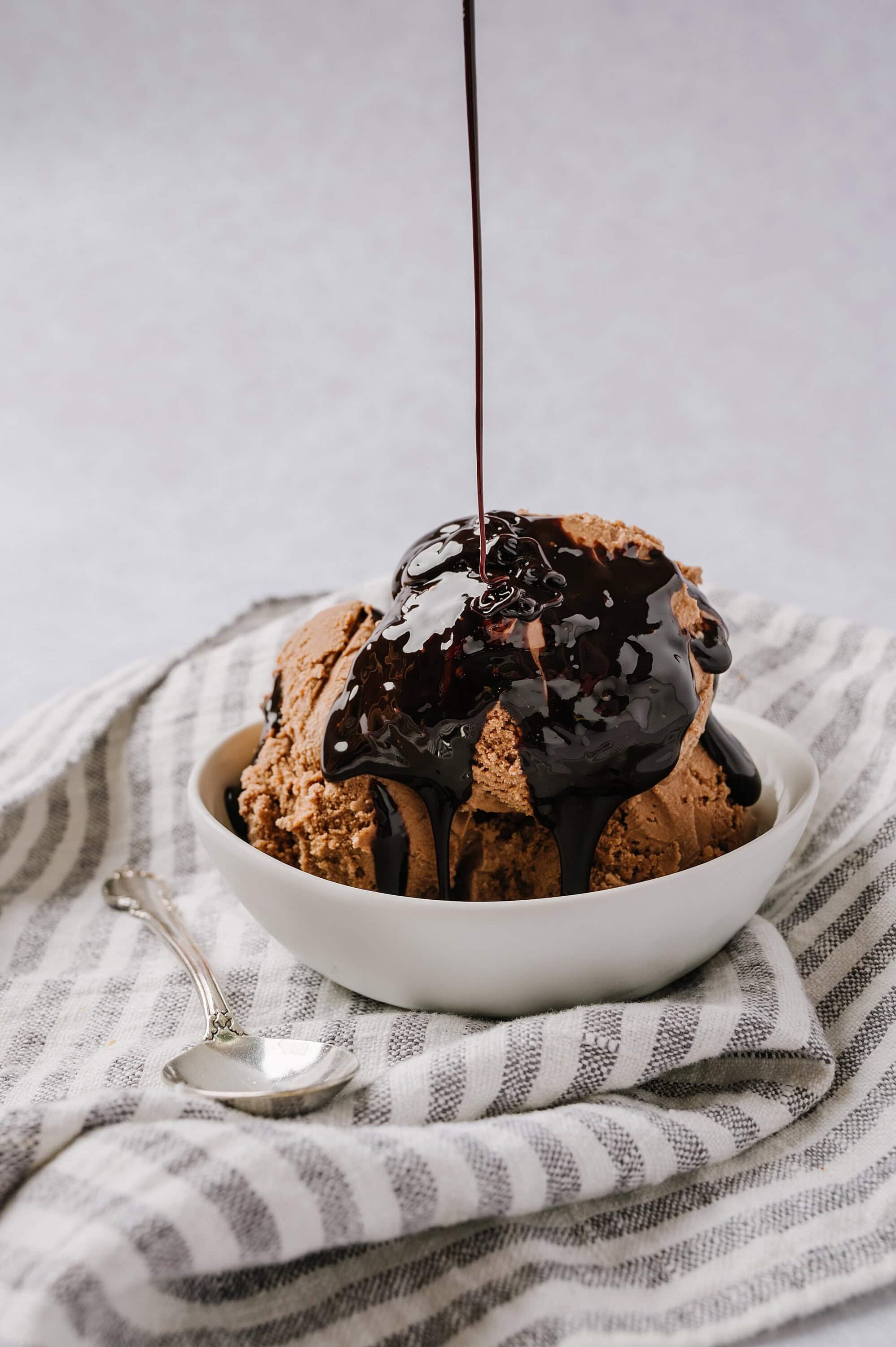 Decadent chocolate ice cream sundaes topped with glossy chocolate syrup in a white bowl. Perfect treat for dessert lovers.