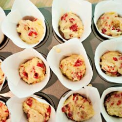Fresh raspberry muffin batter in paper cups ready for baking, featured on Baked Bree.