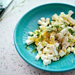 Creamy cheese salad with herbs on a vibrant blue plate, ready to serve.