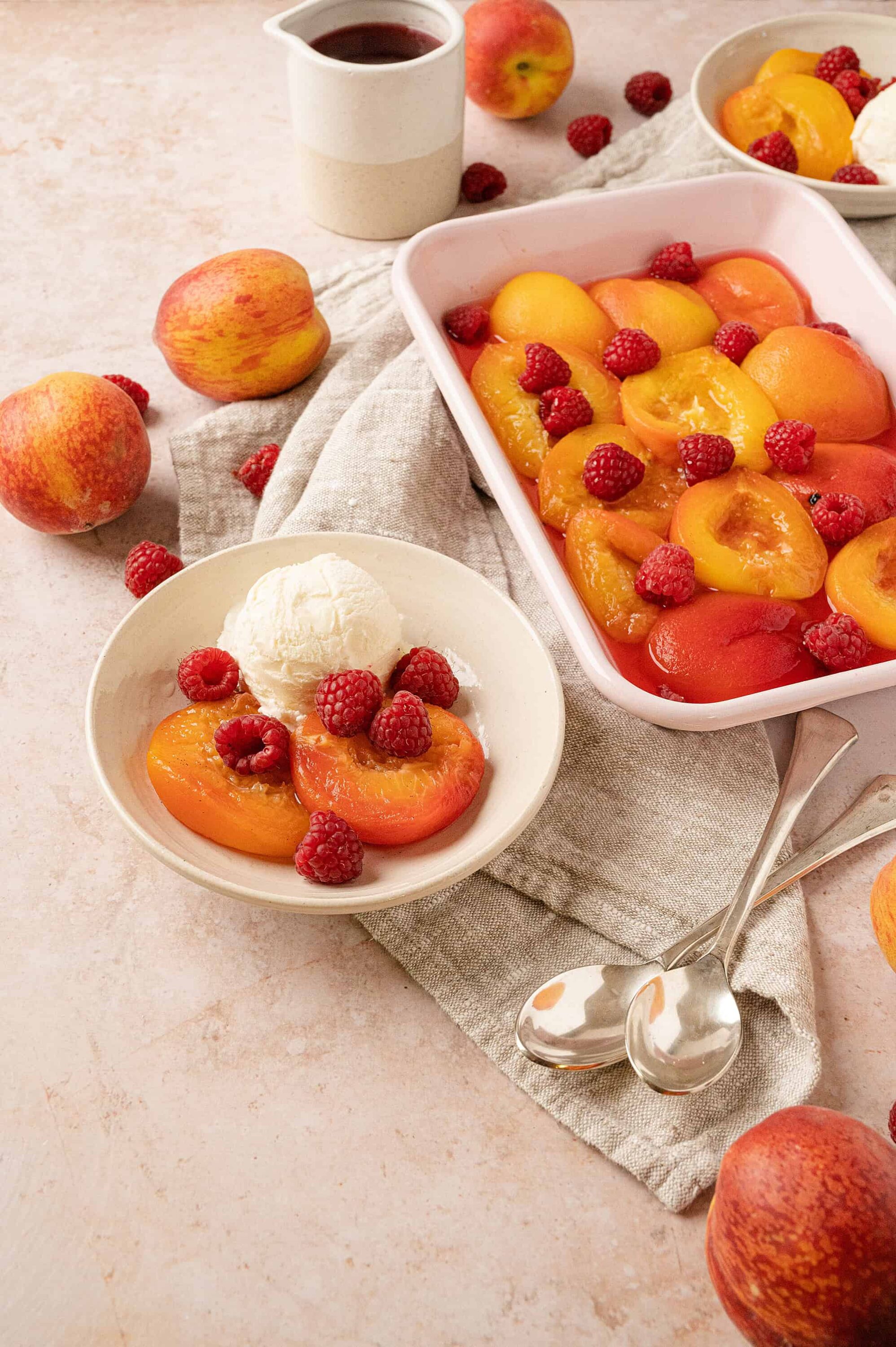 Sweet peach raspberry cobbler with vanilla ice cream on a rustic table, perfect for summer desserts.
