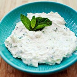 Fresh homemade herbed yogurt dip served in a bright blue bowl, garnished with mint leaves. Perfect for snacks and appetizers.