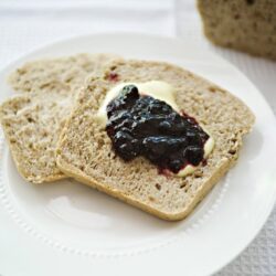 Cream cheese spread with blueberry jam on a slice of whole wheat bread.