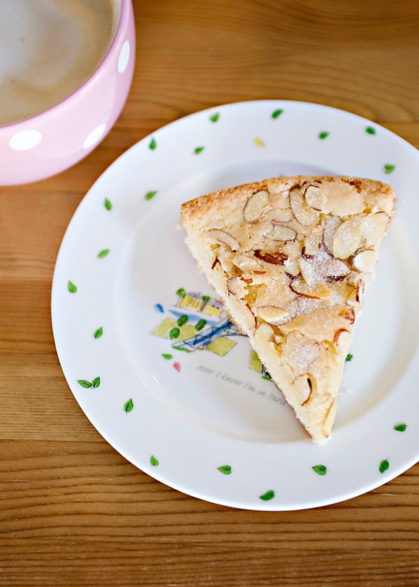 Buttery almond tart on a decorative plate with coffee in a pink cup, close-up of homemade dessert, bakedbree style, delicious almond pastry.