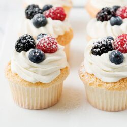 Fresh berry cupcakes with whipped cream and mixed berries on top, perfect for dessert or special occasions.