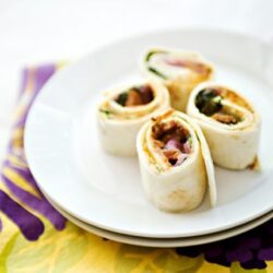 Freshly made turkey and vegetable wraps on a white plate, perfect for healthy lunches.