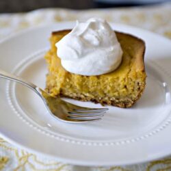 Creamy pumpkin pie topped with whipped cream on a white plate, perfect for fall desserts and holiday gatherings.