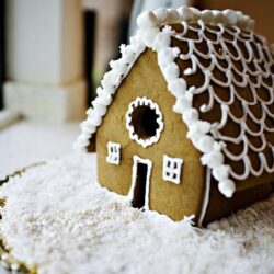 Gingerbread house decorated with white icing on snowy surface for holiday baking.