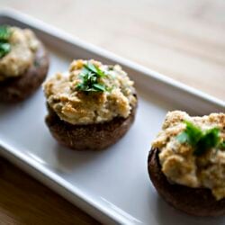 Baked stuffed mushrooms with creamy filling and fresh herbs on white tray.