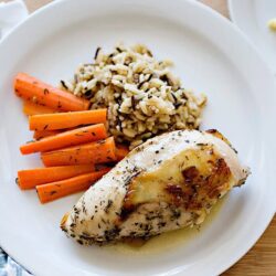 Tender baked chicken breast with rice and carrots on a white plate, healthy dinner idea from Baked Bree.