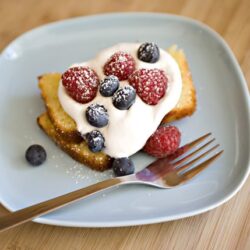 Fresh berry French toast with whipped cream and blueberries on a blue plate.