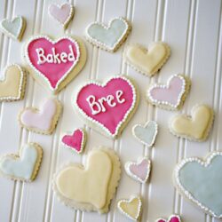 Soft pastel heart-shaped cookies with "Baked Bree" lettering on a white surface.