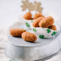 Fried Irish potato candies with cinnamon sugar on a metal cake stand for St. Patrick's Day.