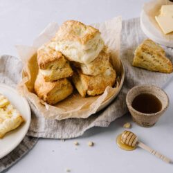 Fluffy homemade scones with clotted cream and honey on a rustic linen. Perfect for breakfast or tea time.