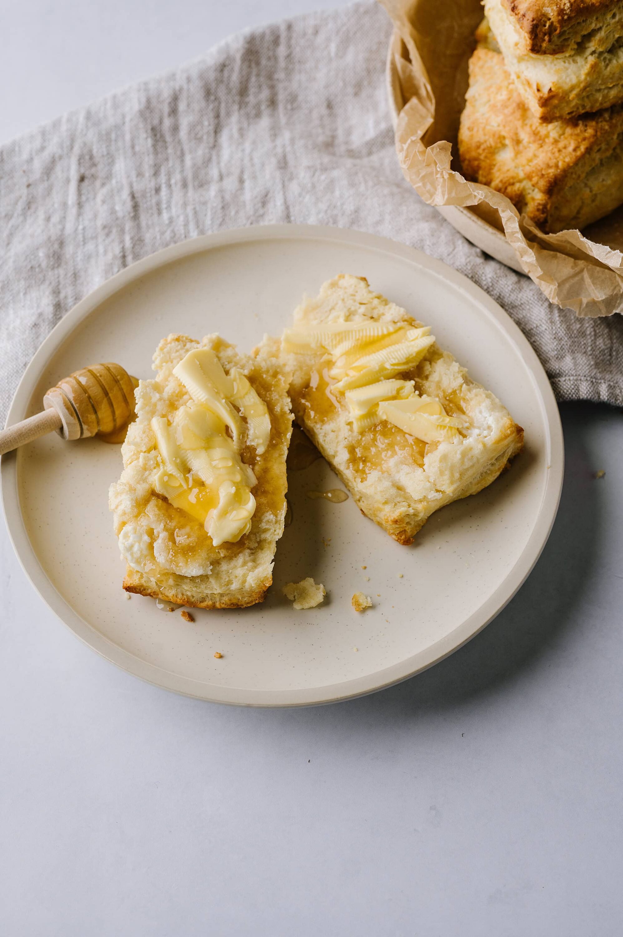 Fluffy buttered homemade bread with honey on a white plate.