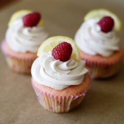 Delicious raspberry lemon cupcakes with whipped frosting on parchment paper. Perfect for spring and summer desserts.