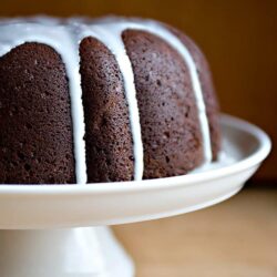 Rich chocolate bundt cake with white glaze drizzled on top.
