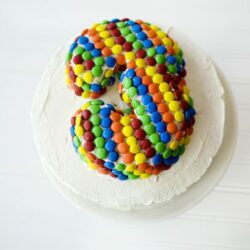 Colorful candy-coated birthday cake with rainbow sprinkles, perfect for celebrations and special occasions.