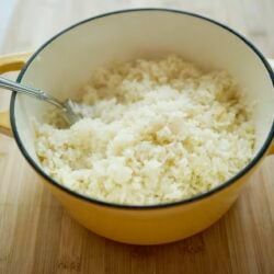 Creamy mashed potatoes in a yellow cooking pot on a wooden surface.