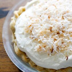 Creamy coconut cream pie topped with toasted coconut flakes and whipped cream.