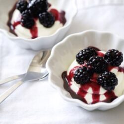 Fresh blackberry and vanilla pudding dessert in elegant white bowls with berry syrup drizzle.