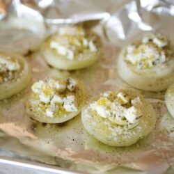 Deviled eggs topped with chopped eggs and seasoning, baking on a foil-lined tray. Perfect appetizer or party snack.