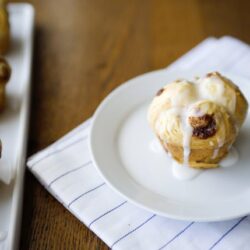 Fluffy cinnamon rolls with icing on a white plate, fresh baked breakfast treat.