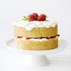 Fresh strawberry layered cake with whipped cream and fruit garnish, perfect for special occasions.