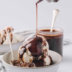 Butter squeeze bottle with chocolate syrup and vanilla ice cream in a bowl.