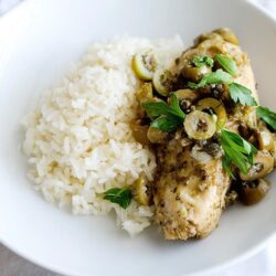 Juicy chicken breast with green olives and fresh herbs served with white rice.