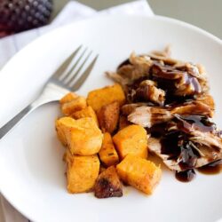 Roast chicken with sweet potato hash and balsamic glaze on white plate.