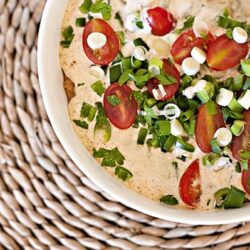 Fresh tomato and green onion dip garnished with chives on a white bowl, ideal for appetizers and snacks.