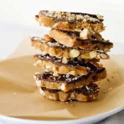 Chewy peanut butter chocolate caramel bars stacked on parchment paper.