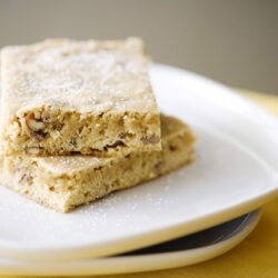 Butterscotch Pecan Blondies with a dusting of powdered sugar on a white plate.
