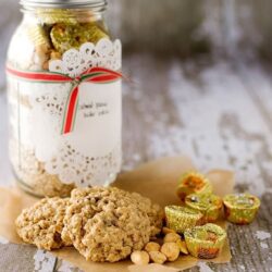Butterscotch cookies with peanut candies and wrapped chocolates on rustic wooden surface, baked goods for holiday treat.