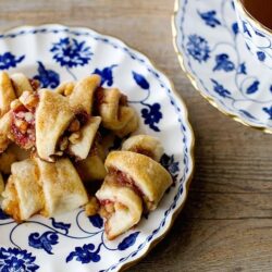 Golden apple cinnamon rolls served on a blue and white floral china plate with tea.