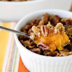Homestyle pumpkin pie filling in a white ramekin with pecans and crumble topping.