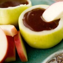Cream cheese stuffed apples with caramel sauce on a decorative plate.