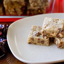 Soft layered protein bars with chocolate chips on a white plate, homemade healthy snack recipe.