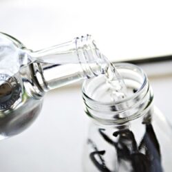 Baking soda being poured into a glass jar for baking recipe.