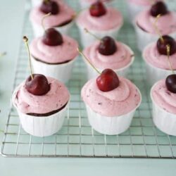 Fresh cherry cupcakes with pink frosting on a cooling rack, perfect for dessert.