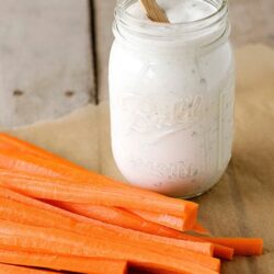 Creamy homemade ranch dip in a Mason jar with fresh carrot sticks for healthy snacking.