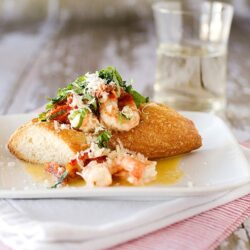 Crunchy fried cod fish with lobster remoulade on a white plate, served with a glass of water.