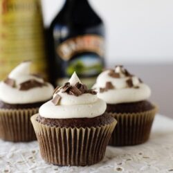 Decadent chocolate cupcakes with vanilla frosting and chocolate shavings on top.