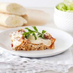 Creamy chicken and rice casserole with melted cheese served on a white plate, garnished with fresh parsley.