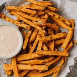 Crispy sweet potato fries with toasted marshmallow dip served on parchment paper.