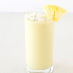 Creamy Piña Colada cocktail with pineapple garnish in a tall glass.