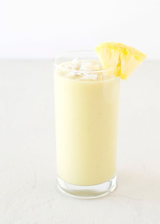 Creamy Piña Colada cocktail with pineapple garnish in a tall glass.